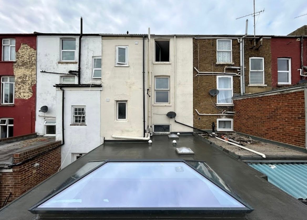 Completed seamless EPDM rubber flat roof with a glass roof lantern on a rear extension