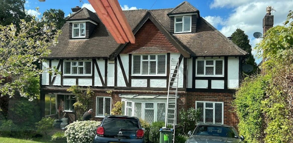 Detached house with heavy moss growth across the tiled roof before roof moss removal