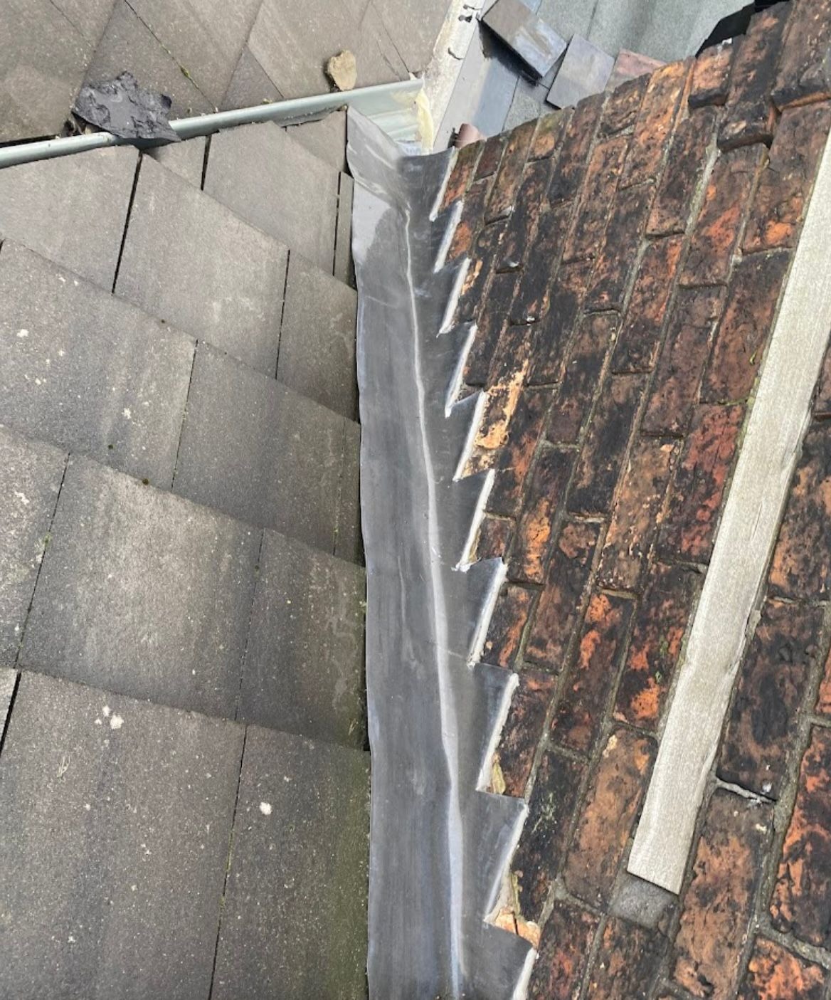 New lead flashing dressed into brickwork at a roof-to-wall abutment after leadwork by SL Roofing Services