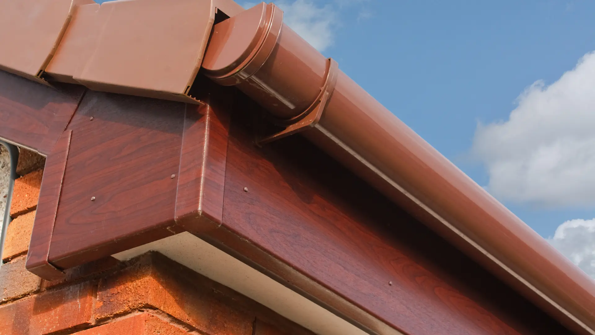 New UPVC fascia, soffit and gutter with downpipe outlet fitted along the roofline of a brick house